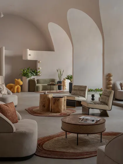 Another perspective of the main lounge area, highlighting the mix of textures from handcrafted wooden stools, plush sofas, and patterned rugs, all under the gentle curve of the vaulted ceiling.