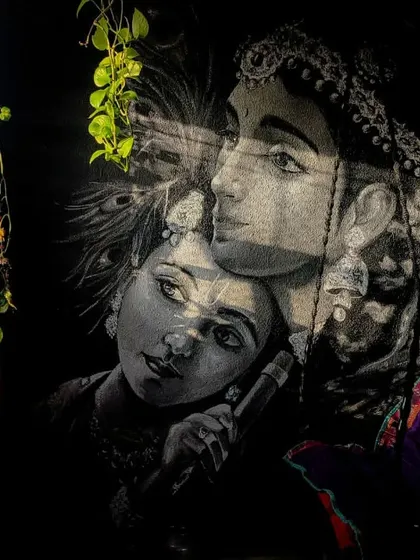 The Krishna mural seen with natural light and shadows from a nearby plant. This shows how the artwork interacts with its environment, changing its mood throughout the day.