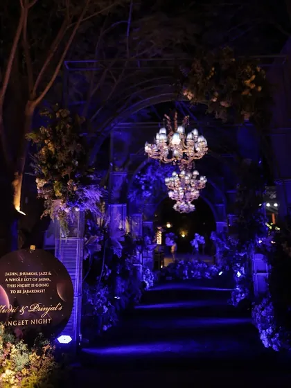The entrance to the moonlight-themed Sangeet, with a dramatic arched walkway, hanging chandeliers, and deep blue lighting that creates a sense of mystery and romance.