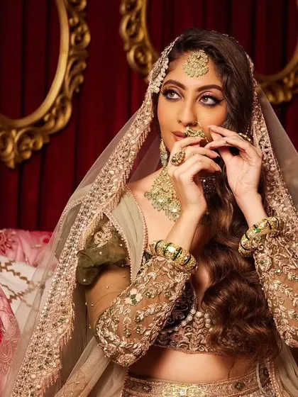A close-up of the modern bride, showing the intricate passamer and nath. The makeup is kept soft to balance the heavy jewelry.