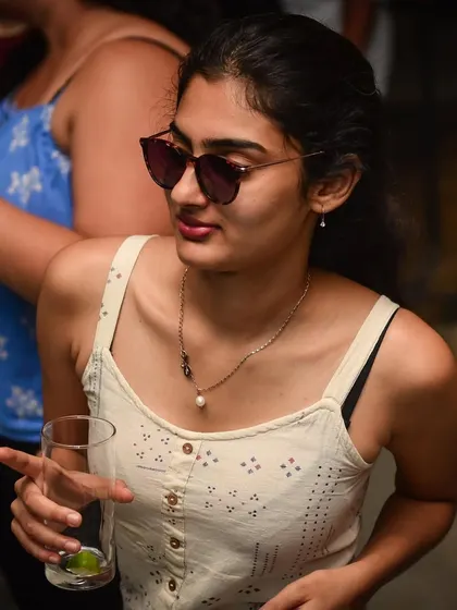 A woman with a drink, enjoying the music. A relaxed and happy partygoer.