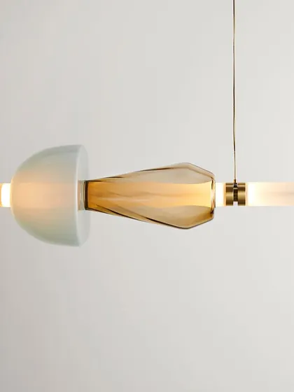 A close-up of a single Luna Kaleido element, showing the combination of a semi-translucent dome and a textured, amber-colored glass piece.