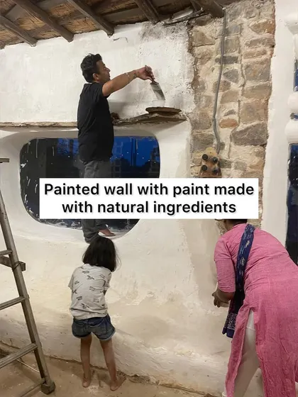 A volunteer painting a wall with natural, chemical-free paint during our community building event. It's a beautiful and healthy alternative to toxic commercial paints.