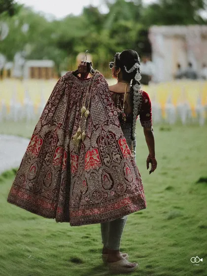 A duplicate of the bride carrying her lehenga from behind.