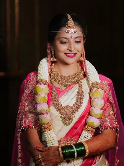 A portrait of the bride in her beautiful pink and white saree, her smile gentle and serene.