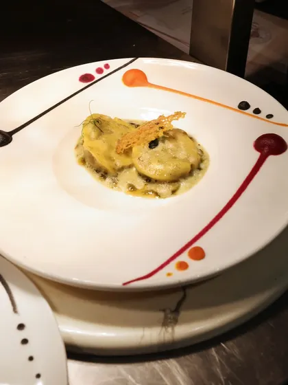 A beautifully plated ravioli dish, with a colourful, abstract design painted on the rim of the plate. This is another example of how we turn the plate into a canvas.