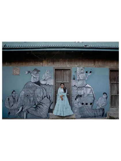 A full-width shot of the bride against the quirky and charming mural, showcasing her outfit and the unique location.