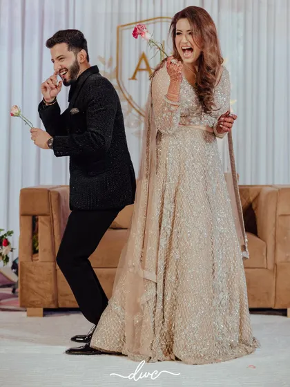 A fun and quirky portrait of the engaged couple, striking a playful pose back-to-back with roses in hand.