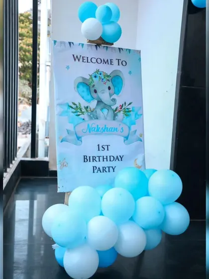 A welcome sign for Nakshan's first birthday party, featuring a sweet baby elephant illustration.
