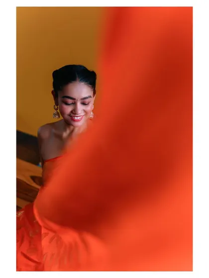 An artistic shot using a piece of orange fabric to frame the subject. This creative composition adds a layer of mystery and playfulness to the portrait.