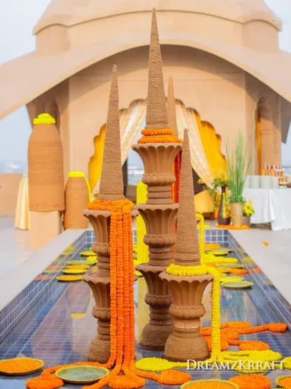 Terracotta spires decorated with marigold garlands are placed in a water feature, adding a unique and artistic element to the Haldi decor.