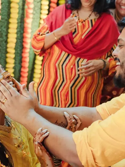 A brother or friend playfully applying Haldi to the bride's face, a moment of family fun.