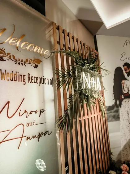A grand and personalized welcome for a wedding reception. This setup features a large welcome sign with the couple's names, their monogram, and a beautiful pre-wedding photo.