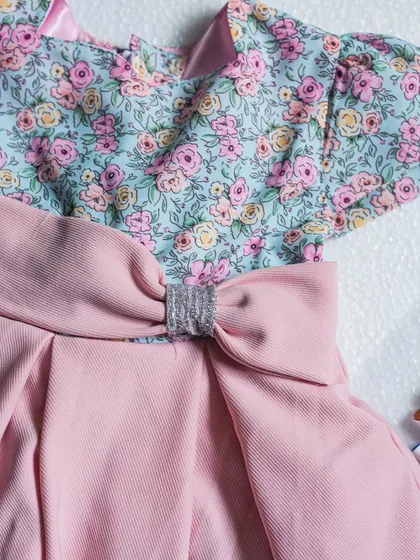 A close-up of the sparkly detail on the bow of this pink floral dress. It's a small touch that adds a lot of charm.