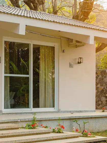 A detail of the Amberle farmhouse, showing the use of natural stone walls and a simple, elevated porch. The design is intentionally subtle to let the beauty of the surrounding landscape take center stage.