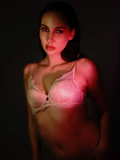 Using a soft red light to illuminate the delicate lace of the lingerie. The focus is on texture and form, creating a sensual but not explicit image.