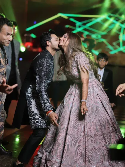 A spontaneous, happy kiss on the dance floor. This candid moment is full of life, love, and the energy of their celebration.