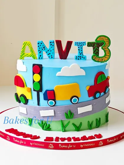 A fun and colorful vehicle-themed cake for a 3rd birthday. This design features a fondant road with cars, a truck, and a traffic light, perfect for any little one who loves things that go.