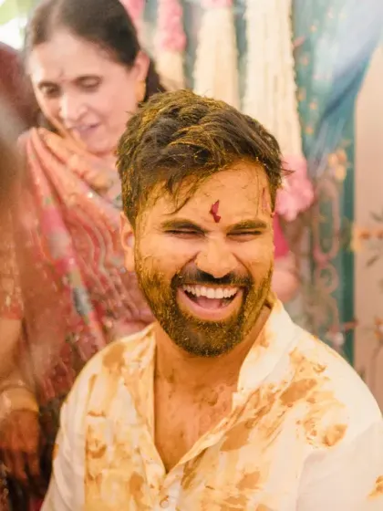 The groom's face is a mask of laughter as he gets covered in haldi. This candid shot is full of the uninhibited joy that makes haldi ceremonies so special.