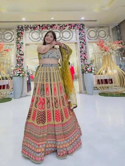 A full view of the client in the multi-colored printed lehenga, posing at a wedding venue. It's a versatile outfit that works for various festive settings.
