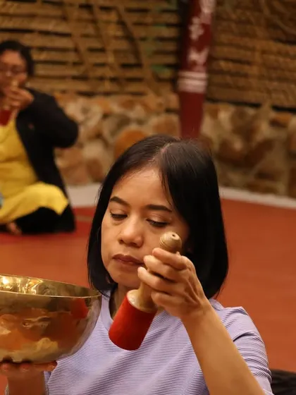 A participant deeply focused on creating resonant sounds with her singing bowl.