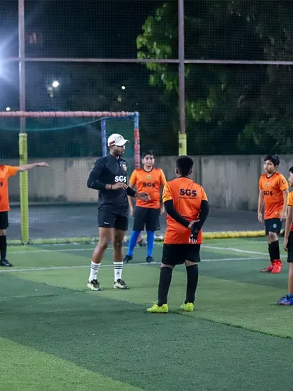 A coach giving tactical instructions to the team during a break in training. We focus on developing intelligent football players.