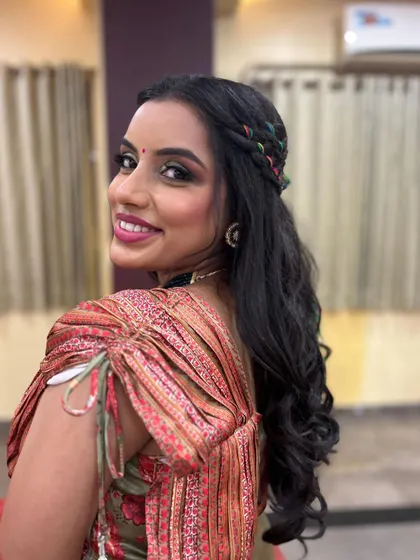 A smiling portrait of the bride, her eyes sparkling with glam makeup and her hair styled in a fun, modern braid.