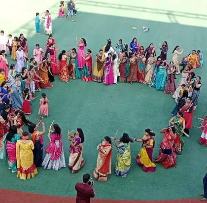 Mothers and children form a large circle to dance with dandiya sticks, a vibrant display of community participation.