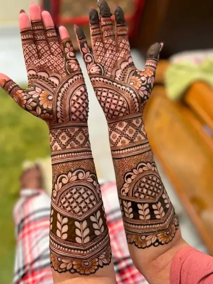 A beautiful example of a fully developed henna stain. This design features bold leaf patterns on the arms and intricate checkerboard fills on the hands.