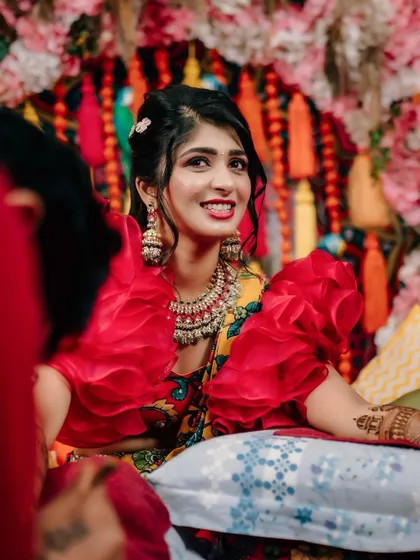 The bride's radiant smile during her Mehendi ceremony. The decor is designed to enhance the joy of the occasion, with every detail contributing to the festive mood.