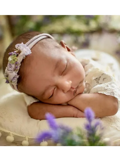 A close-up on the baby's face in the lavender-themed shoot, highlighting the delicate floral headband.