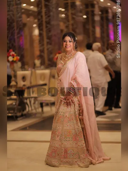 A full-length shot of the bride's mami in her elegant pastel lehenga. The soft pink dupatta and intricate embroidery make it a sophisticated choice.