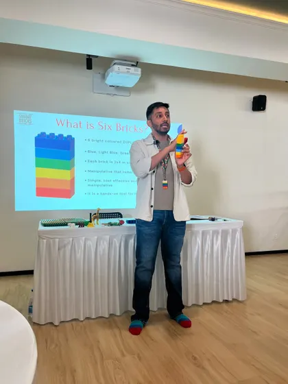 The workshop leader demonstrates a build, explaining the pedagogical purpose behind the activity. Every fun game in my training is backed by solid educational principles.
