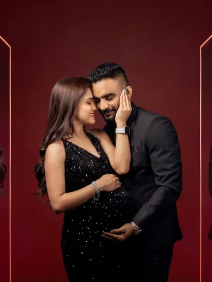 An intimate and glamorous shot of a couple, with the mom-to-be sparkling in a black sequin dress.