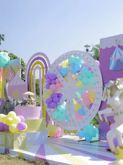 A wide shot of the outdoor pastel carnival stage. The setup includes a large Ferris wheel, carousel horses, and rainbow arches, creating a complete wonderland on the lawn.