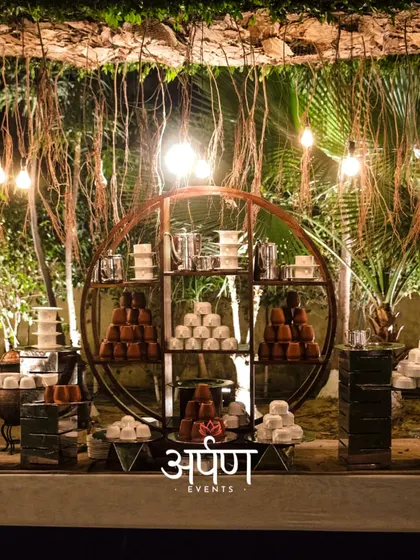 A stunning dessert and beverage station with rustic-chic decor, featuring an array of traditional Indian sweets and drinks.