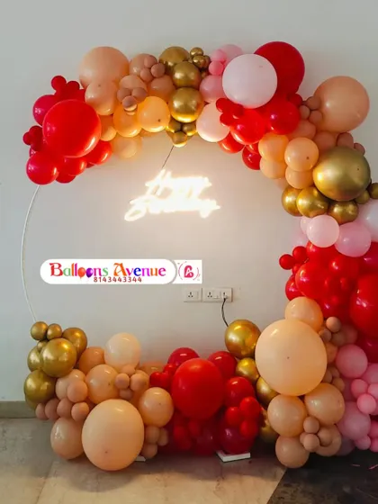 A close-up of the red and gold balloon arrangement with the 'Happy Birthday' neon sign glowing in the center.