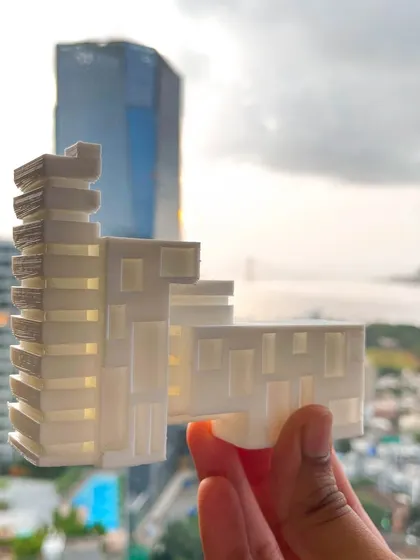 This 3D-printed model showcases a more detailed design concept with articulated facades and stepped massing. Holding the model against the city view helps us visualize how the future building will interact with its surroundings and the skyline.