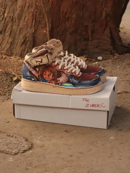 A full view of the Chucky-themed sneakers. The coffee-dyed base gives the shoes a grimy, aged look that perfectly fits the horror theme.