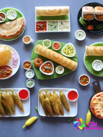 A beautiful flat lay of various Indian food miniatures, including dosa, chole bhature, pizza, and vada pav.