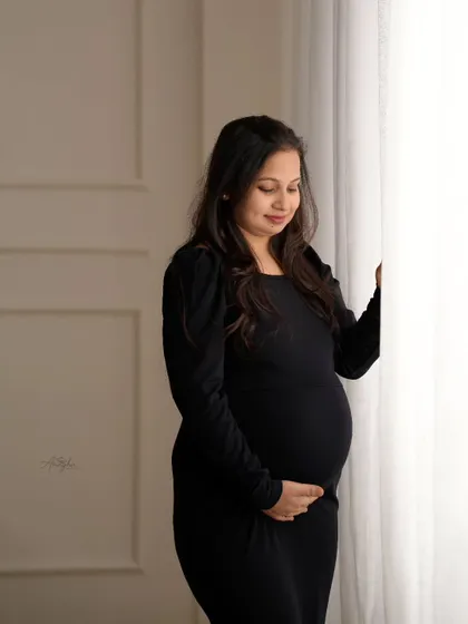 A contemplative portrait by the window. The soft light and the mother's gentle expression create a peaceful and beautiful image.