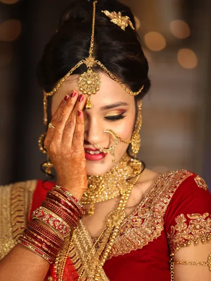 A candid and shy smile from a bride in her gorgeous red and gold wedding lehenga.