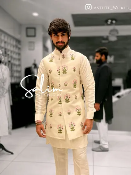 A client wearing an off-white kurta set with a matching Nehru jacket that features delicate floral embroidery. A perfect choice for a sophisticated daytime event.