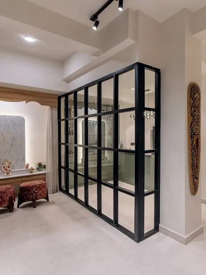 A stylish glass partition separates the bar area from the pooja space in 'Project Lily', creating distinct zones while maintaining an open feel.