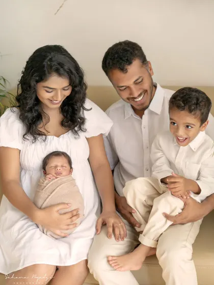 A beautiful family of four enjoying a quiet moment together on the sofa. The older brother's happy smile shows how excited he is to have a new sibling.