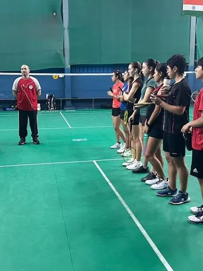 Players from both teams listening intently during a coaching brief. Discipline and respect are core values here.