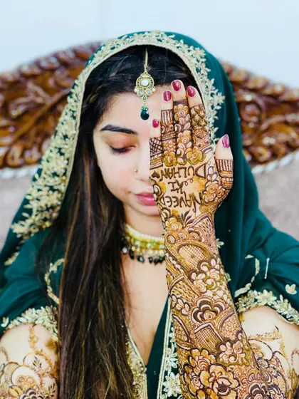 A graceful pose from the bride, showing off her personalized henna and beautiful bridal attire.