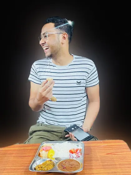 Pure happiness on a plate. A customer is captured mid-laugh while enjoying one of our wholesome thali meals at a table.