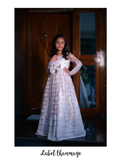 The white lace gown is elegant and timeless. The long sleeves are made of sheer, embroidered fabric.