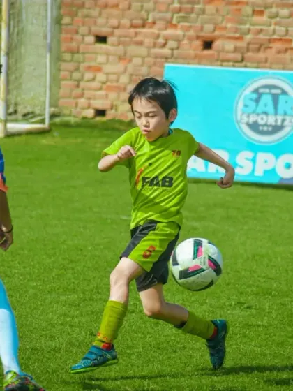 A young player shows off their dribbling skills, controlling the ball with the outside of their foot.